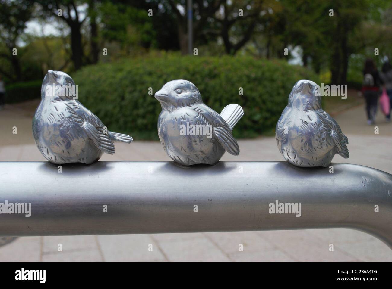 Pequeños pájaros metálicos en una barandilla, arte en el jardín del palacio en Osaka, Japón Foto de stock
