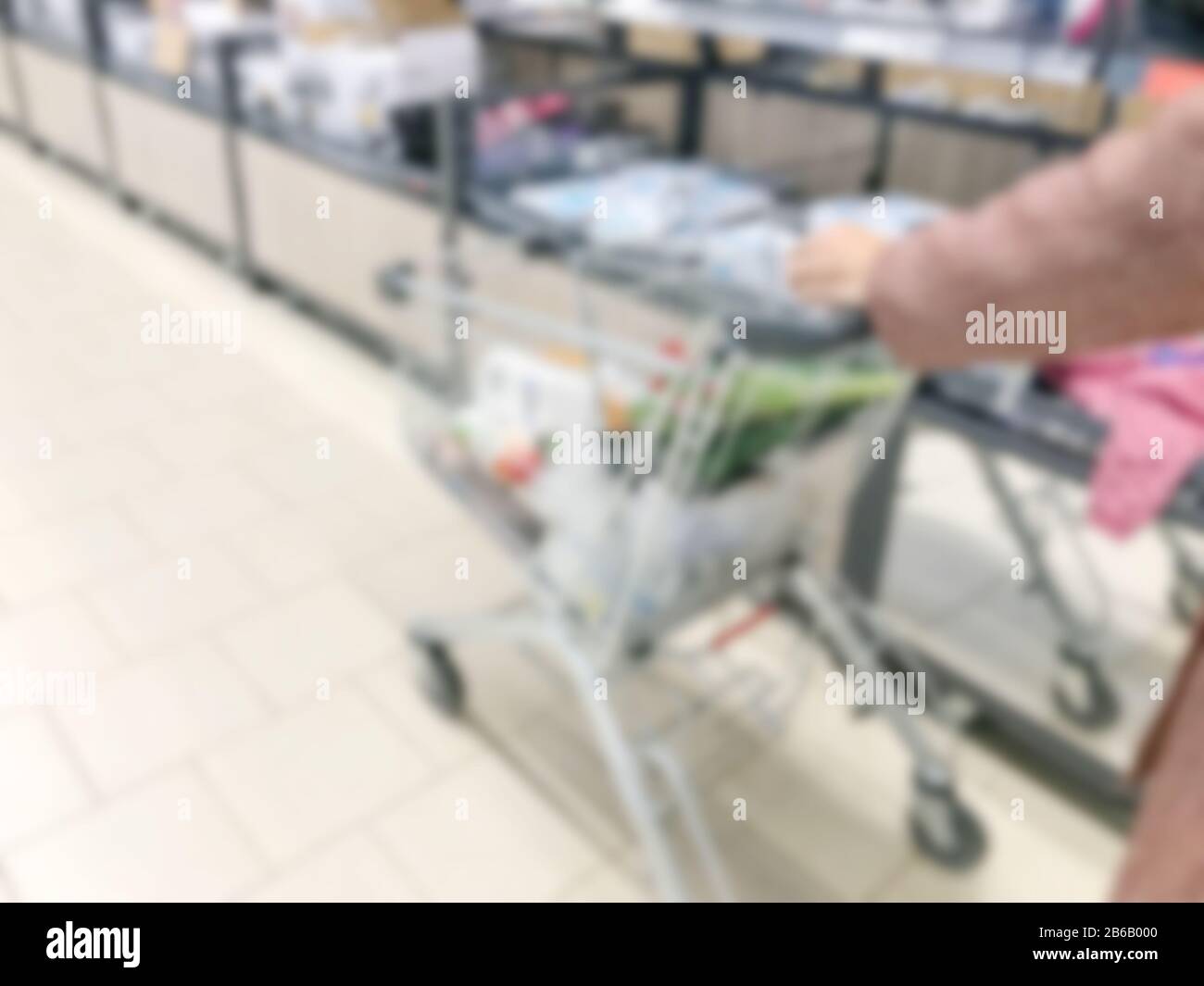 Mujer joven con carrito de compras en el supermercado de la ciudad. Foto de stock