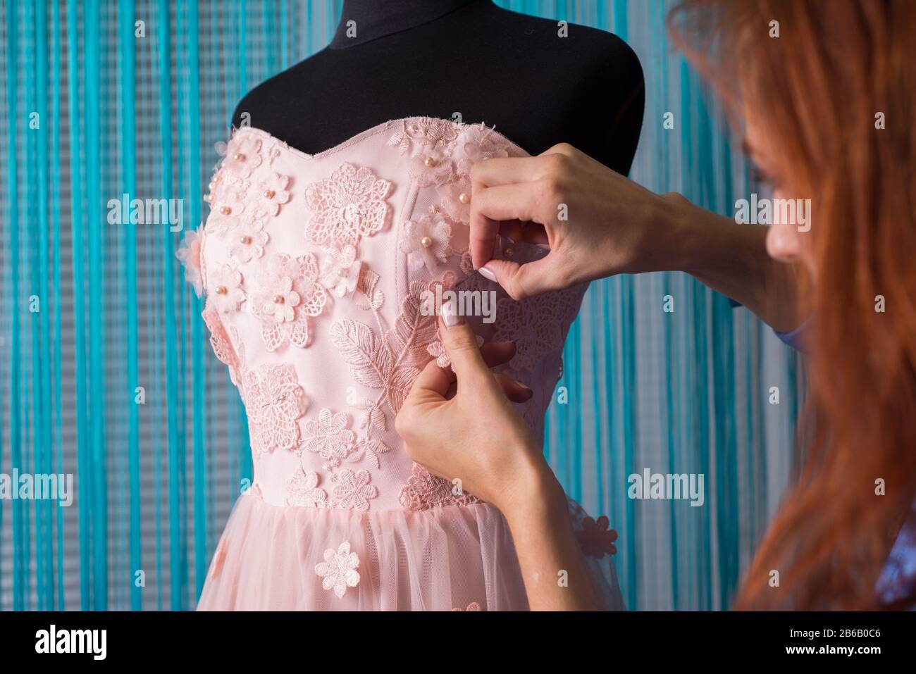 El proceso de confección de ropa. Diseñador profesional, handmade artesano, cose flores en un vestido rosado, sobre un maniquí, en un taller. La sastrería, wome Fotografía de stock - Alamy El proceso de confección de ropa. Diseñador profesional, handmade artesano, cose flores en un vestido rosado, sobre un maniquí, en un taller. La sastrería, wome Fotografía de stock - Alamy
