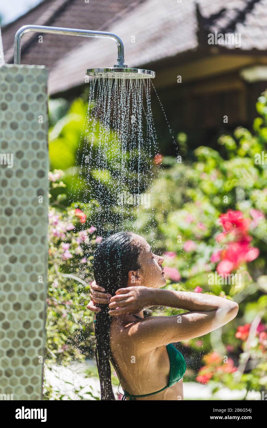 Mujer tomar una ducha exterior en el jardín verde tropical de Bali