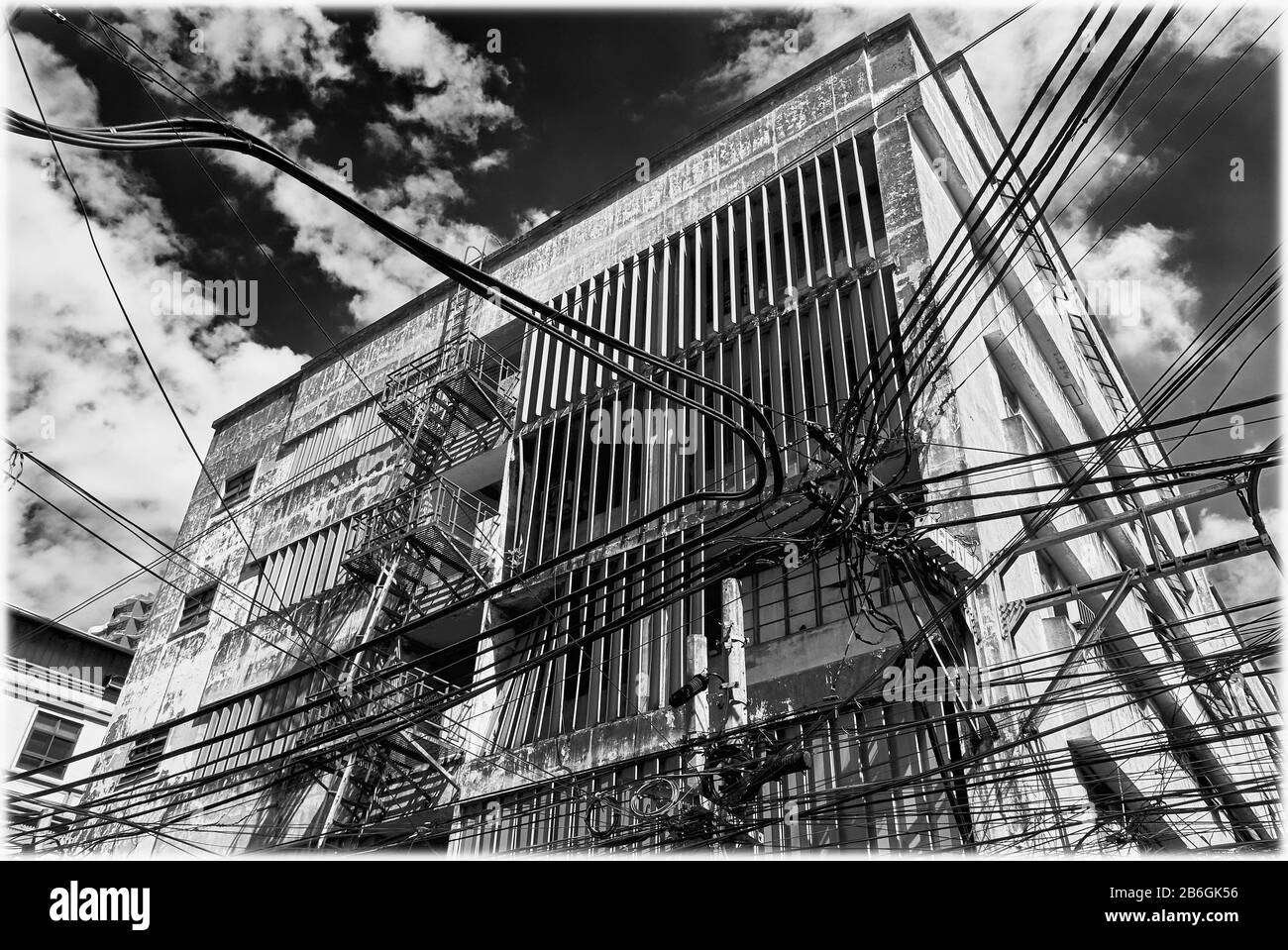 Vista en blanco y negro de un antiguo edificio comercial y un lío de cables, líneas eléctricas en el distrito chino de Binondo, Manila, Filipinas Foto de stock