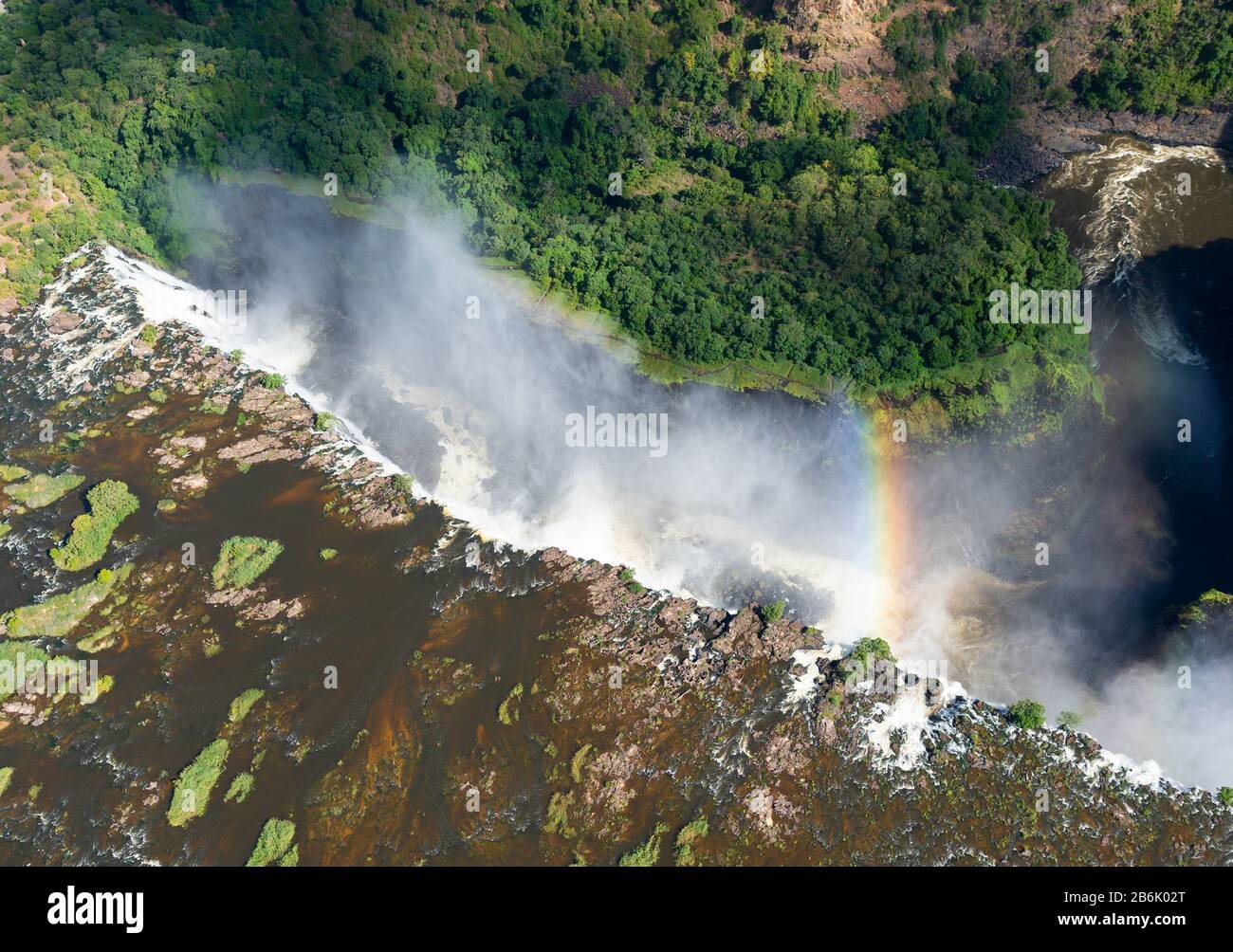 Vista aérea de las Cataratas Victoria en la frontera de Zimbabwe y Zambia en África. Corriente de agua que fluye por un cañón con un arco iris. Río Zambezi. Foto de stock