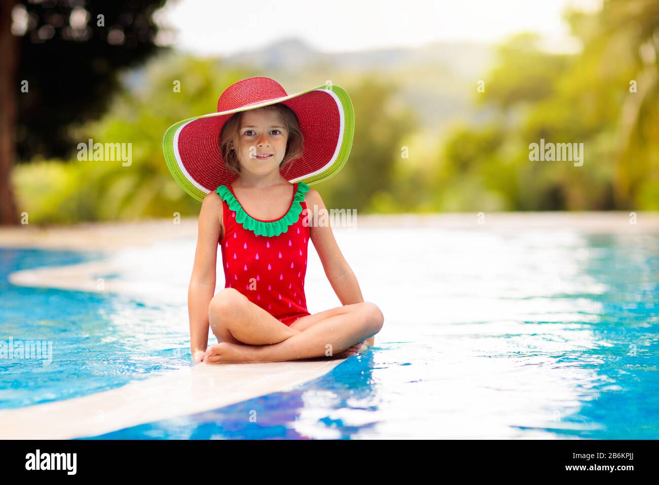 Niños en la piscina. Vacaciones tropicales para familia con niños. Niña  vestidos de rojo sandía bañador y sombrero para el sol jugando en la piscina  de exo Fotografía de stock - Alamy