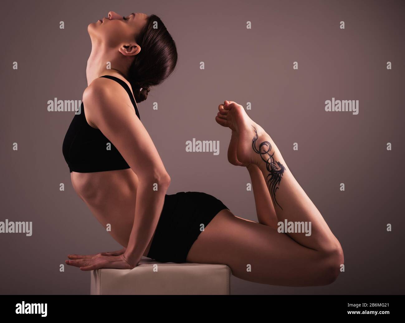 Encantadora chica atleta morena en ropa interior negra hace yoga asana  sentado en un cubo sobre un fondo marrón. Concepto de un estilo de vida  saludable. Publicidad Fotografía de stock - Alamy