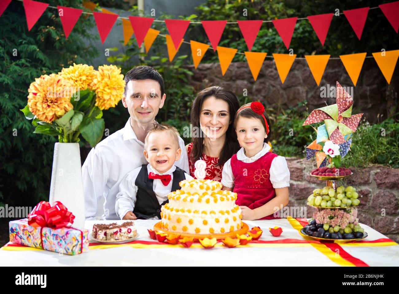 familia de cuatro personas padre mamá hijo e hija celebra el cumpleaños de  su hija tres años sentados en una decoración de mesa festiva y una grande  Fotografía de stock - Alamy