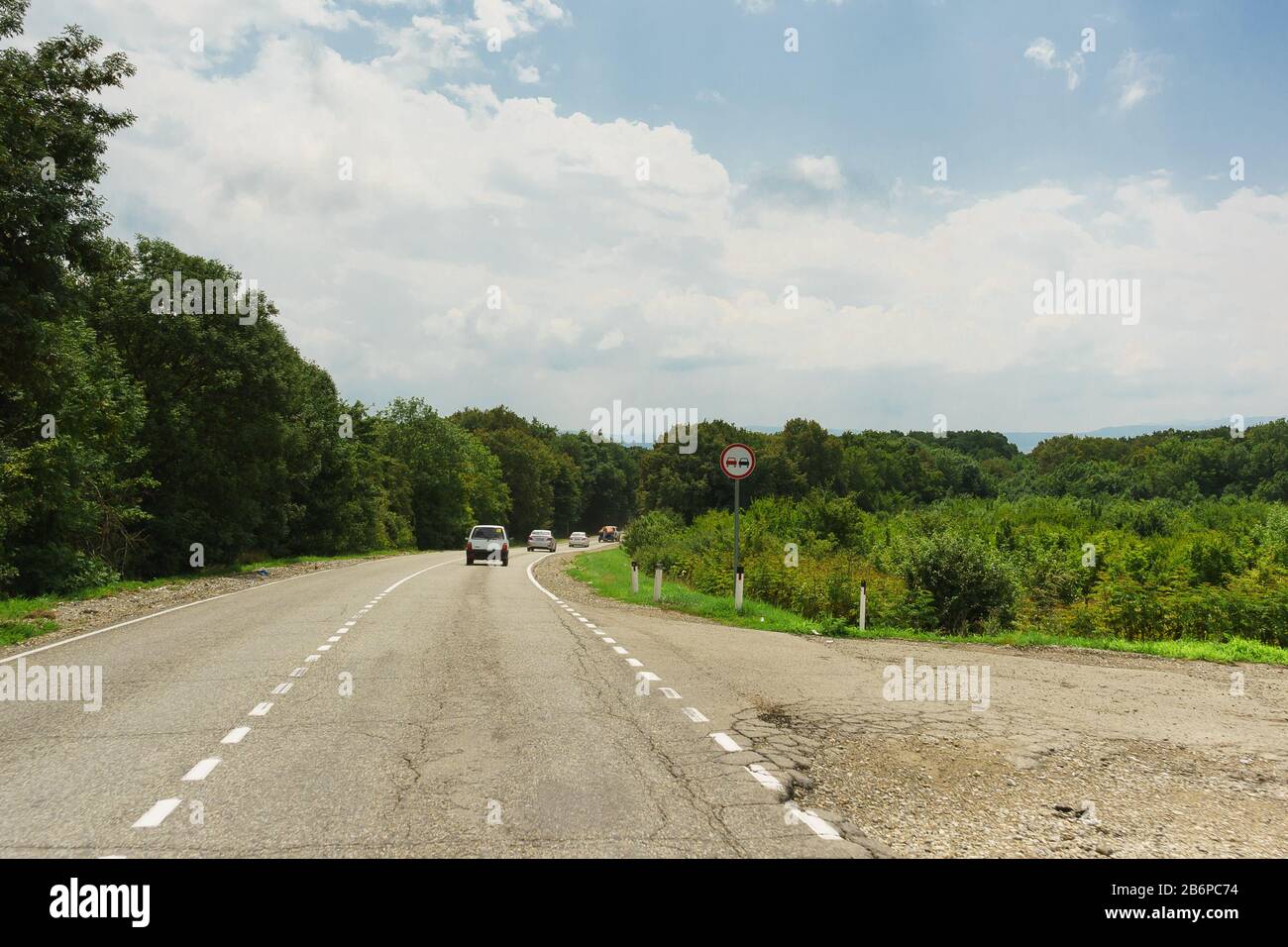 Gire en la antigua carretera en el distrito de Anapa de la región de Krasnodar. Está prohibido Adelantar señales de tráfico. Paisaje en verano día nublado Foto de stock