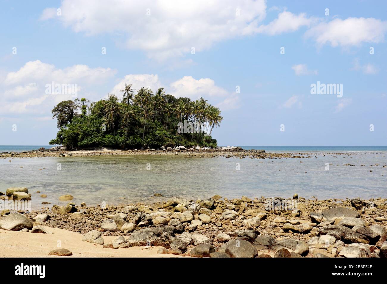 Isla tropical con palmeras de coco en el océano, vista pintoresca desde la playa con rocas. Colorido paisaje marino con cielo azul y nubes blancas Foto de stock