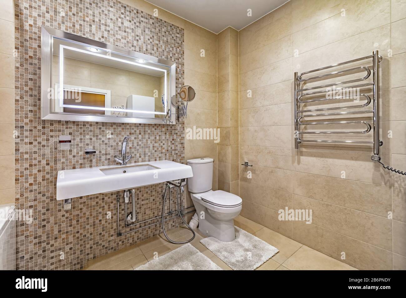 baño moderno, espejo, inodoro y lavabo de cerámica en azulejos beige amplio  y limpio cuarto de baño Fotografía de stock - Alamy
