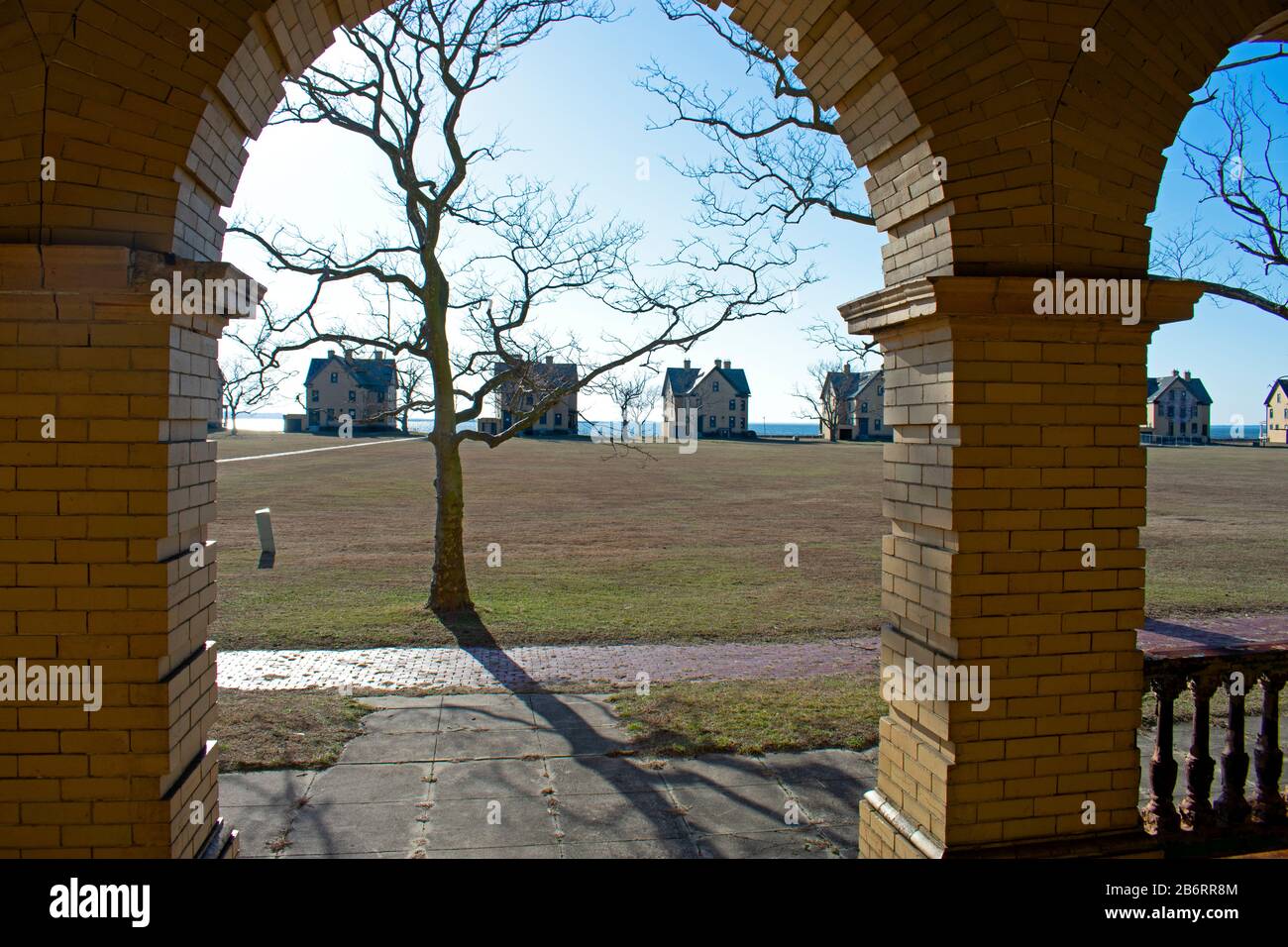 Las siluetas de las casas en fila de oficiales que bordean la orilla de Sandy Hook Bay se ven desde el pórtico de un edificio desocupado detrás de ellas Foto de stock