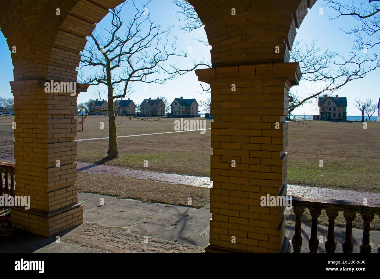 Las siluetas de las casas en fila de oficiales que bordean la orilla de Sandy Hook Bay se ven desde el pórtico de un edificio desocupado detrás de ellas Foto de stock