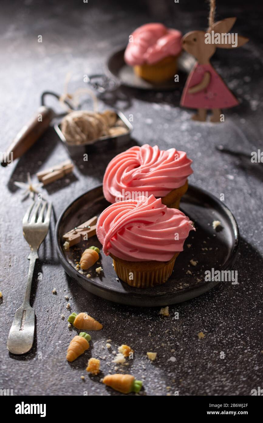 Cupcakes con fruta sabor crema.Pascua postre.conejito de madera en la mesa.comida deliciosa. Foto de stock