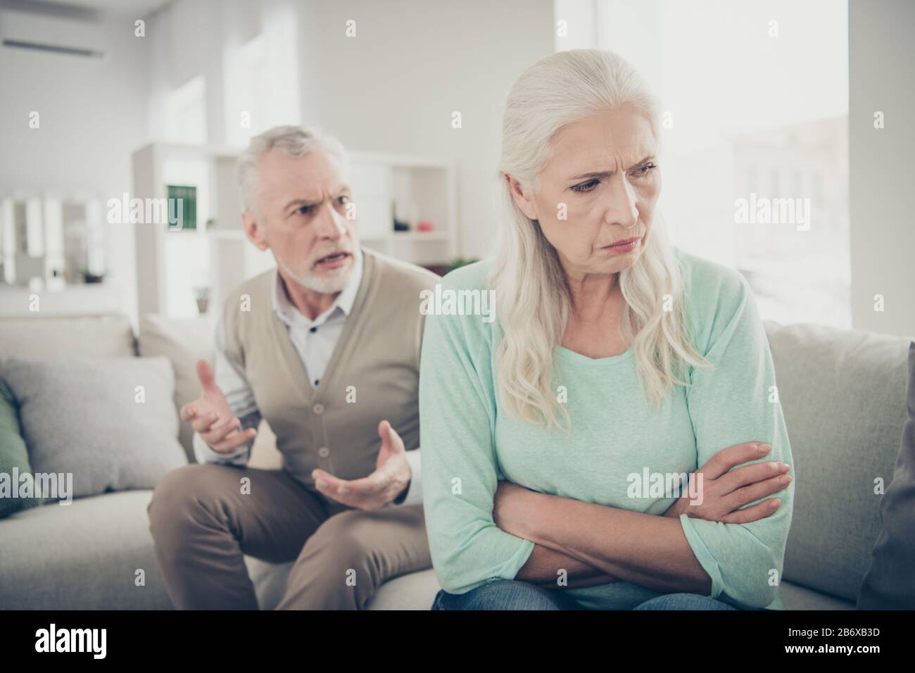 Foto de cerca de la vieja abuela triste y de pelo largo no quiere escuchar a su marido estricto que está enviando reclamaciones Foto de stock