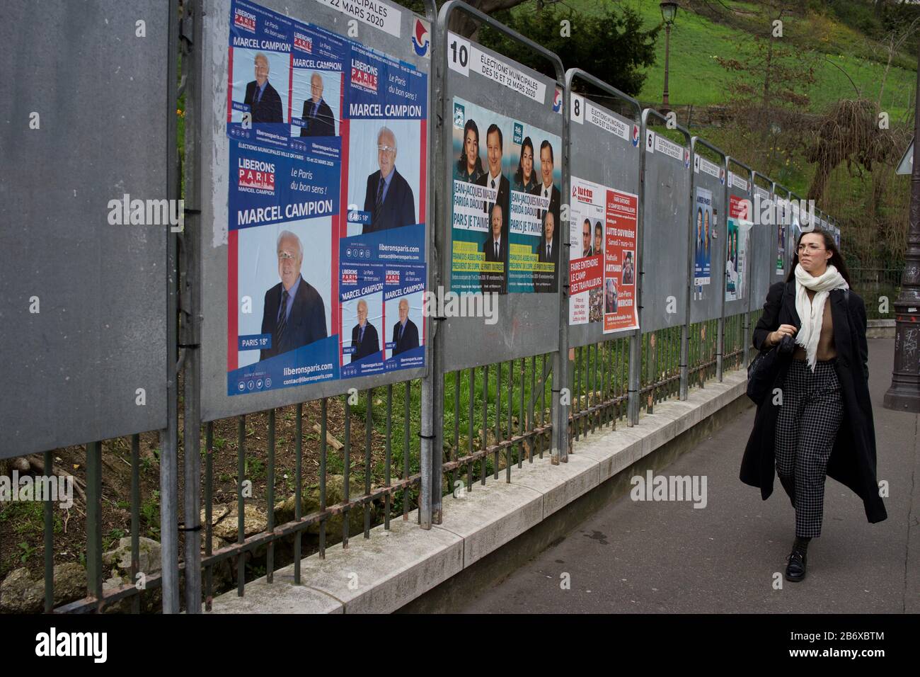 La mujer pasa por los tablones de exhibición mostrando candidatos electorales que se presentan en las elecciones municipales francesas, rue Ronsard, Montmartre, 75018 París, Francia, marzo de 2020 Foto de stock