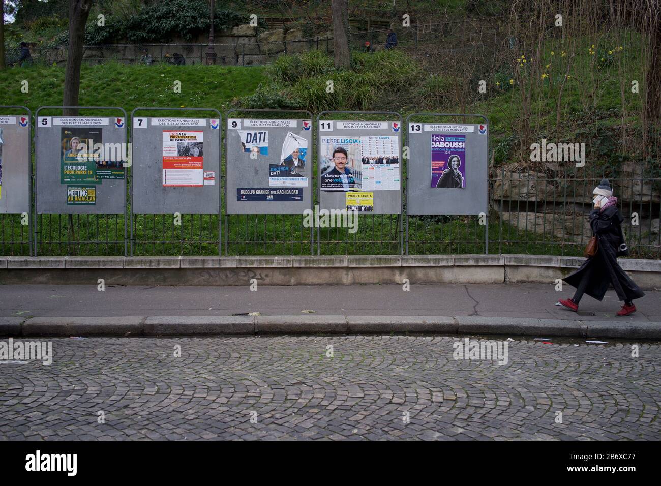 Mujer camina hacia paneles que muestran candidatos electorales en las elecciones municipales francesas, rue Ronsard, 75018 París, Francia, marzo de 2020 Foto de stock