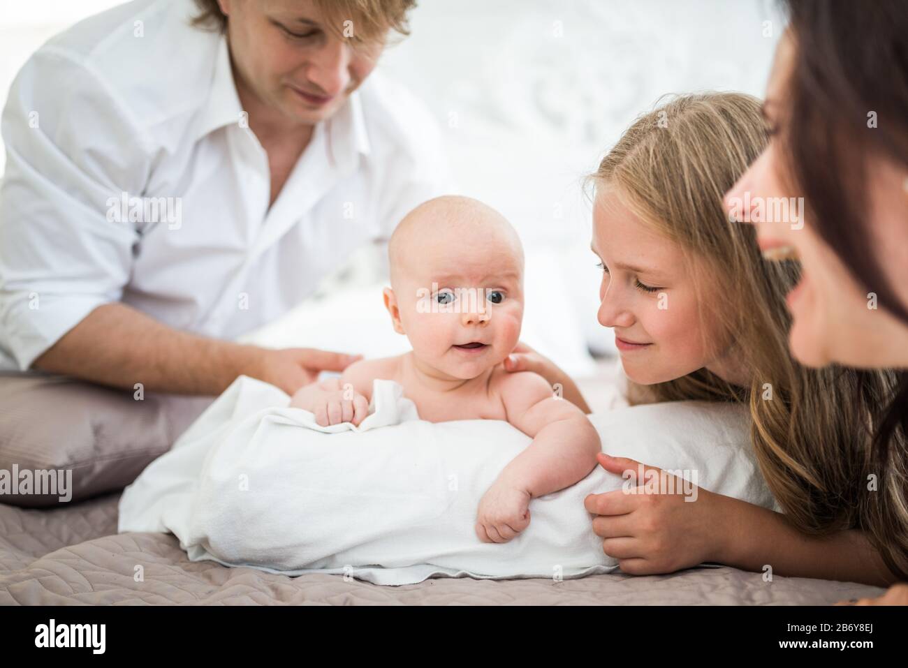 Hermosa Y Sonriente Familia Mama Papa Hija Mayor Y Recien Nacido Estan Tumbados En Una Cama Grande En Un Dormitorio Luminoso Concepto De Familia Caucasica Amistosa Fotografia De Stock Alamy