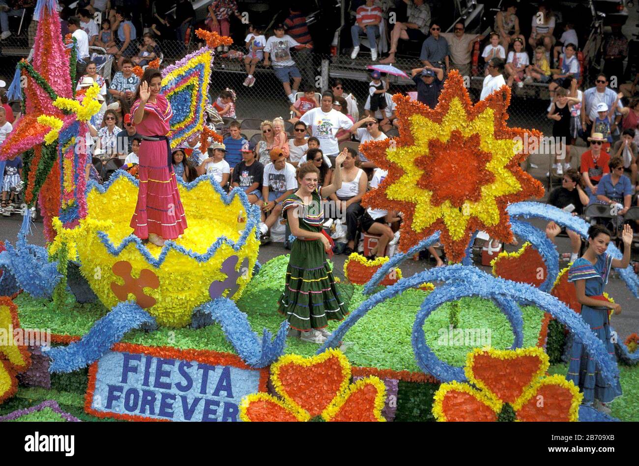 San Antonio, Texas USA: Mujeres jóvenes disfrazadas ondean a la multitud  mientras se montan en un flotador con flores en el desfile de la 'Batalla  de Flores' durante la celebración anual de