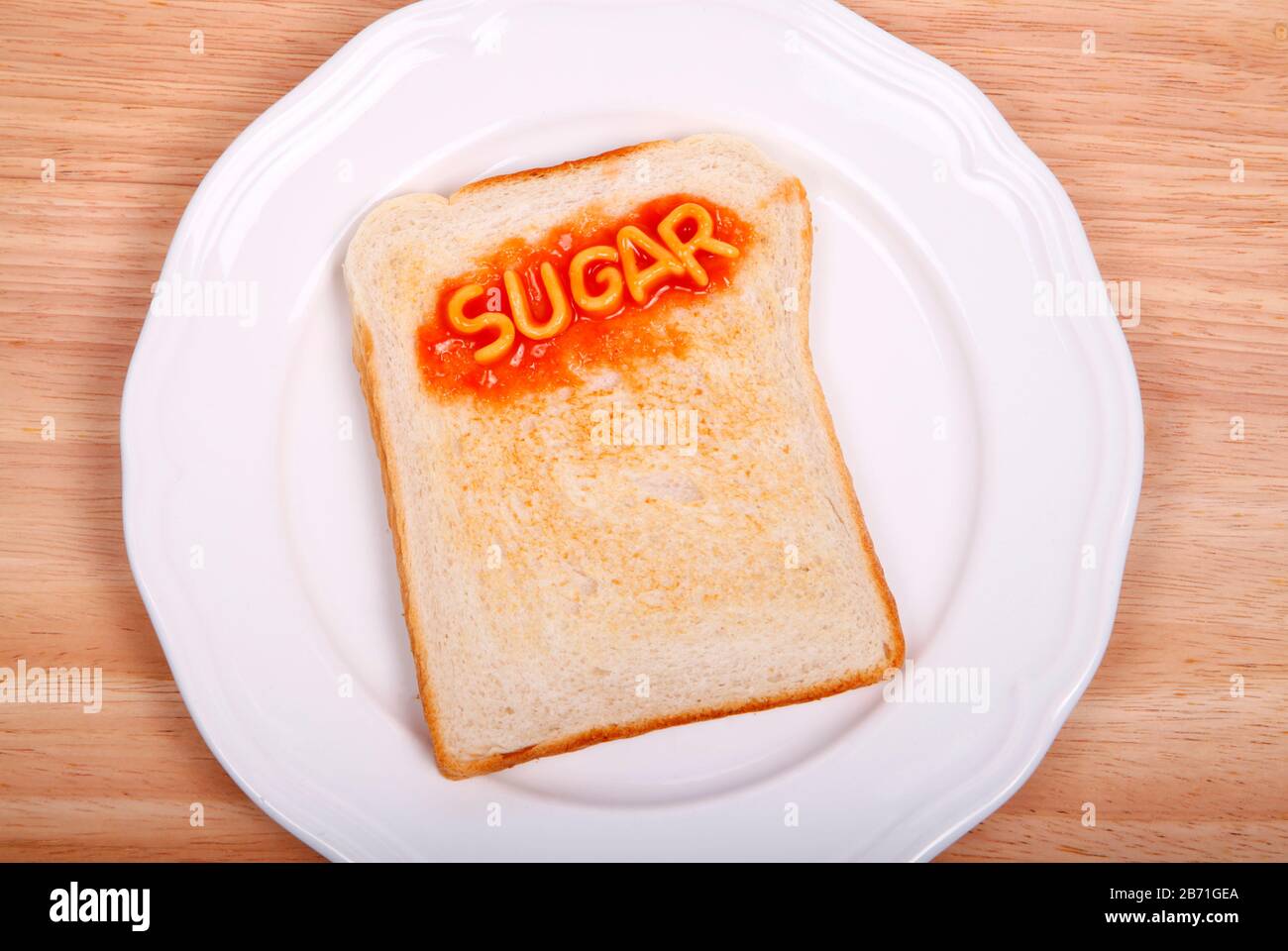 La palabra azúcar deletreada en una rebanada de pan tostado con espaguetis del alfabeto Foto de stock