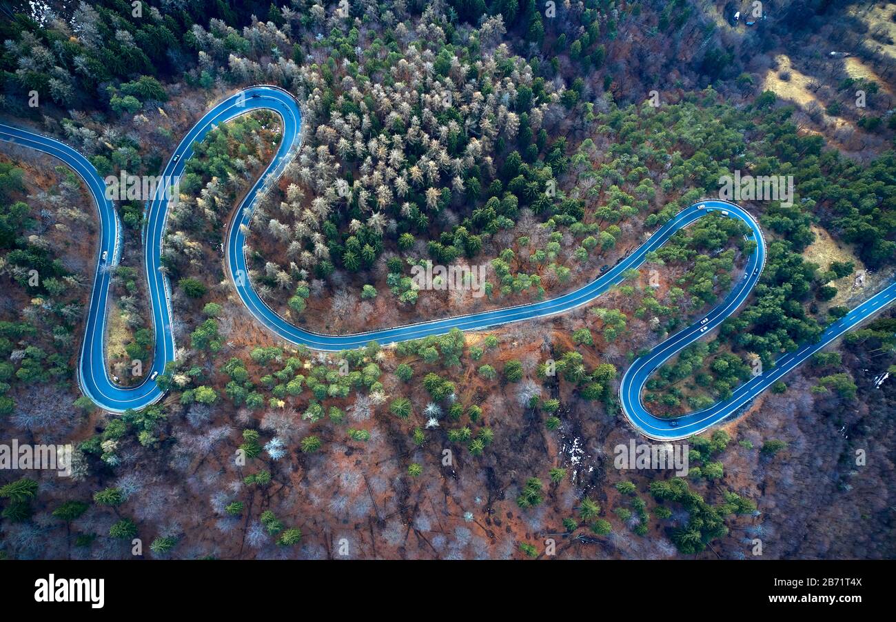La vista aérea de la sinuosa carretera desde el paso de alta montaña con árboles en Transilvania, Rumania, curva de la carretera vista por drone en el otoño-invierno Foto de stock