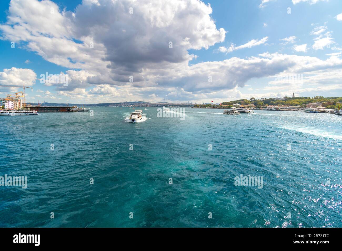 Un pequeño barco turístico recorre el Cuerno de Oro del río Bósforo cerca del puente de Gálata en Estambul, Turquía. Foto de stock