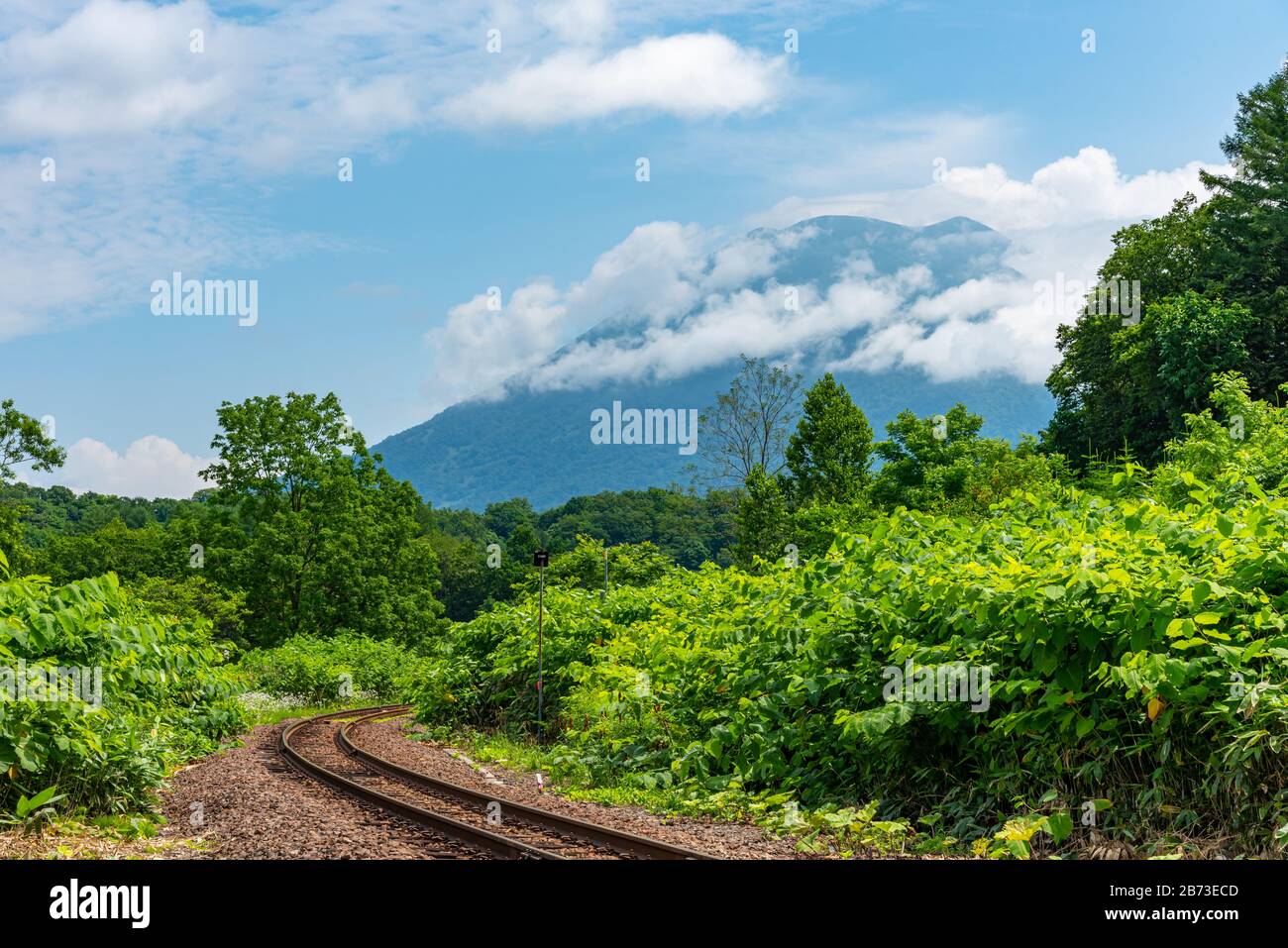 Hakodate línea principal de ferrocarril en la ciudad de Niseko en primavera soleado día con el Monte Yotei en el fondo. Subprefectura de Shiribeshi, Hokkaido, Japón Foto de stock