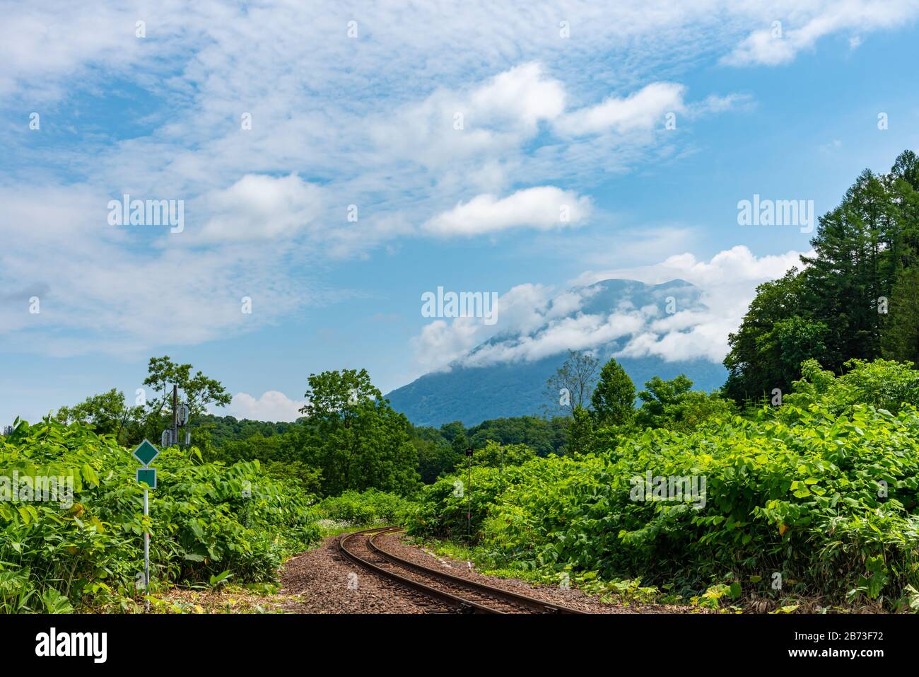 Hakodate línea principal de ferrocarril en la ciudad de Niseko en primavera soleado día con el Monte Yotei en el fondo. Subprefectura de Shiribeshi, Hokkaido, Japón Foto de stock