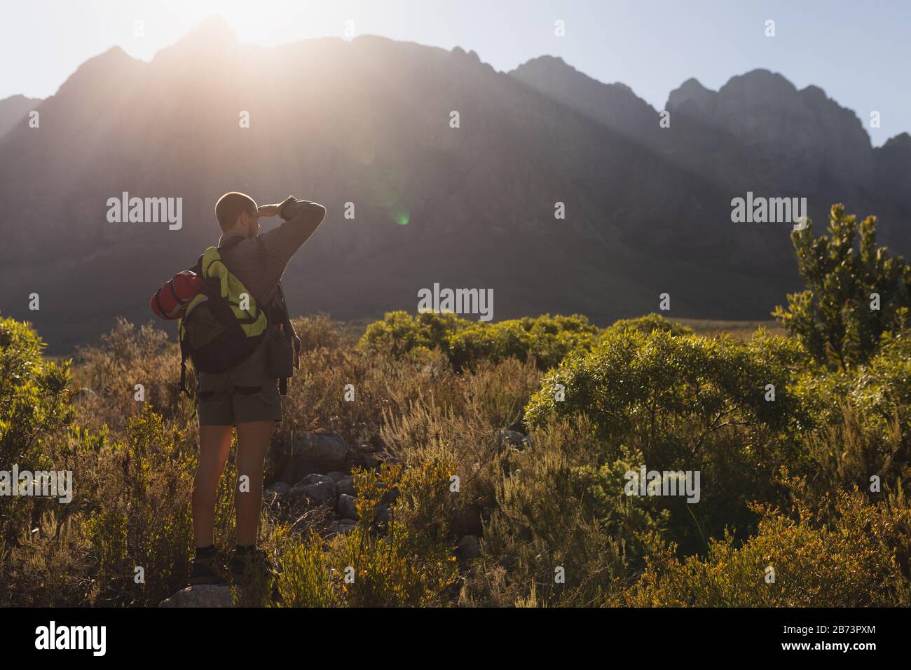 Vista trasera del hombre en una roca mirando hacia fuera Foto de stock