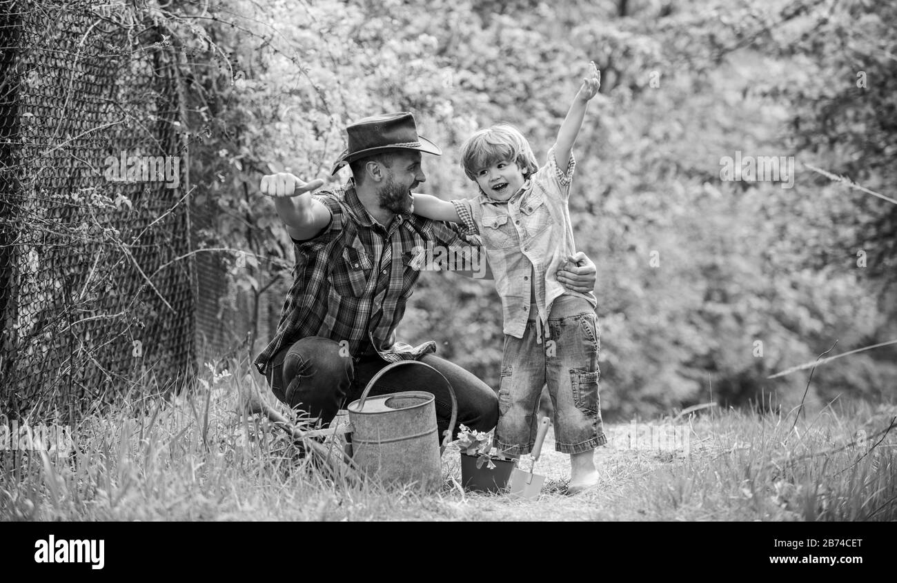 Spring Garden. Papá enseñanza pequeño hijo cuidado de las plantas. Ejemplo personal. Pequeño Ayudante en el jardín. La siembra de flores. El cultivo de plantas. Tenga cuidado de las plantas. Chico y padre en la naturaleza con regadera. Foto de stock