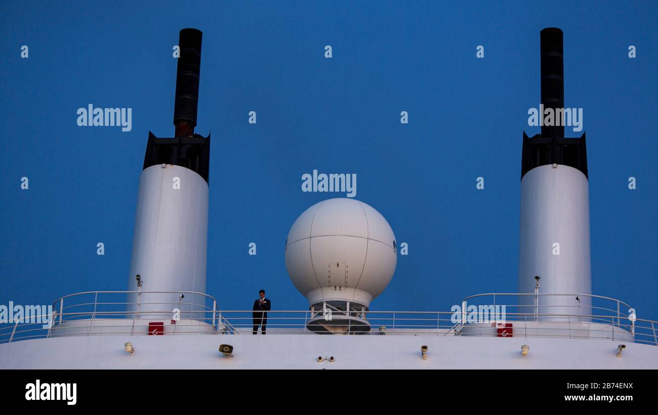 Cruzando el Océano Atlántico desde Brooklyn a Southampton a bordo del transatlántico Queen Mary 2. Los dos tubos de escape para las turbinas de gas a bordo del QM 2 se encienden por la noche. Un hombre en traje puede ser visto por encima del puente de la nave. La bombilla del centro contiene sensores de radar y navegación. Foto de stock