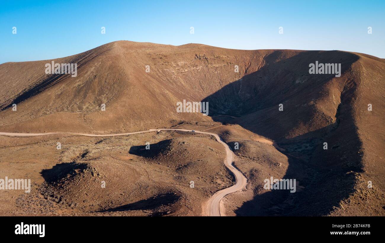 Vista aérea de un camino que conduce a través de una vasta zona de tierra volcánica y montañas Foto de stock