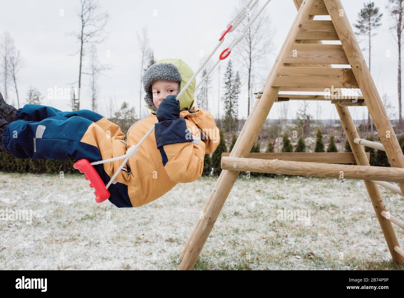 primer plano de un niño que se balancea en un columpio en el exterior en invierno Foto de stock