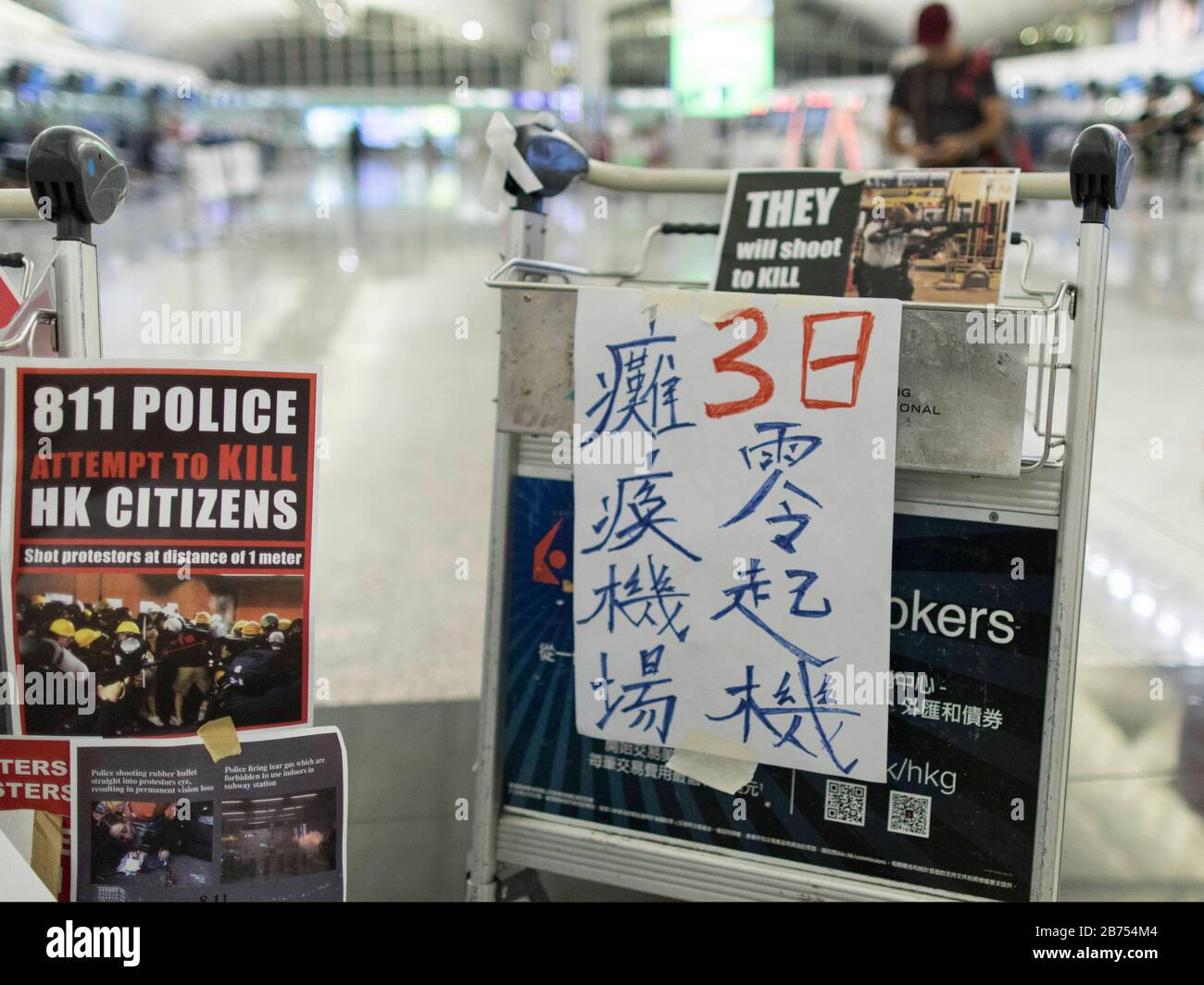 El cartel dice:' Paralizó el aeropuerto durante tres días'. Miles de personas anti-gobierno ocupan el Aeropuerto Internacional de Hong Kong en Hong Kong. Estaban furiosos con un policía que disparó a la vista derecha de una enfermera que causó una ceguera permanente durante su enfrentamiento anoche en Tsim Sha Tsui. Todos los vuelos se cancelaron a última hora de la tarde. Foto de stock