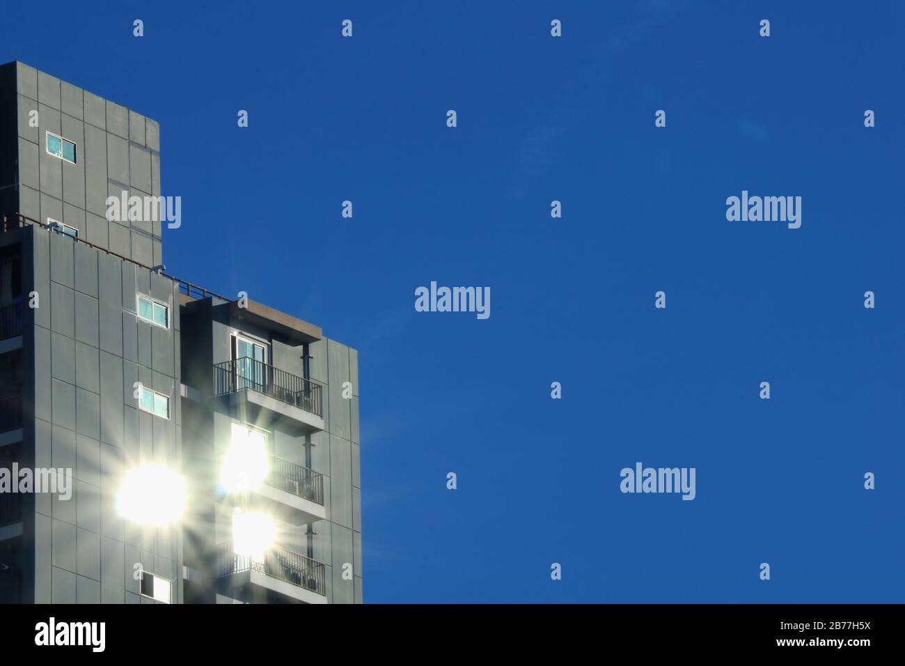 Edificio moderno con reflejos de sol sobre un cielo azul intenso Foto de stock