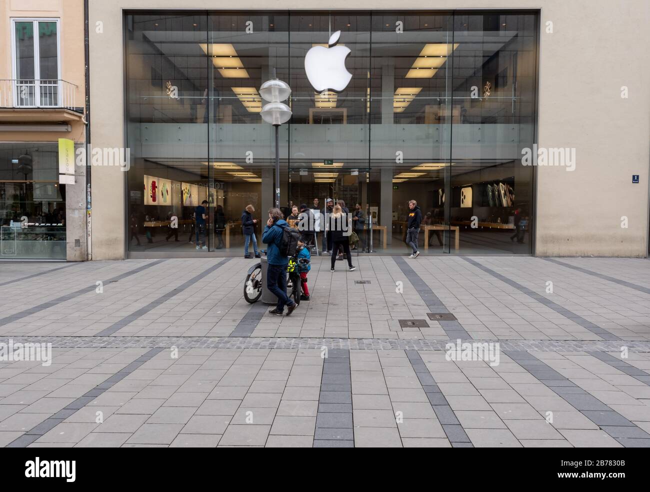 Munich, Alemania. 14 de marzo de 2020. Algunos transeúntes se encuentran frente a la puerta de entrada de un Applestore en el centro de la ciudad. Apple cierra todas las tiendas fuera de China durante dos semanas. Crédito: Peter Kneffel/Dpa/Alamy Live News Foto de stock