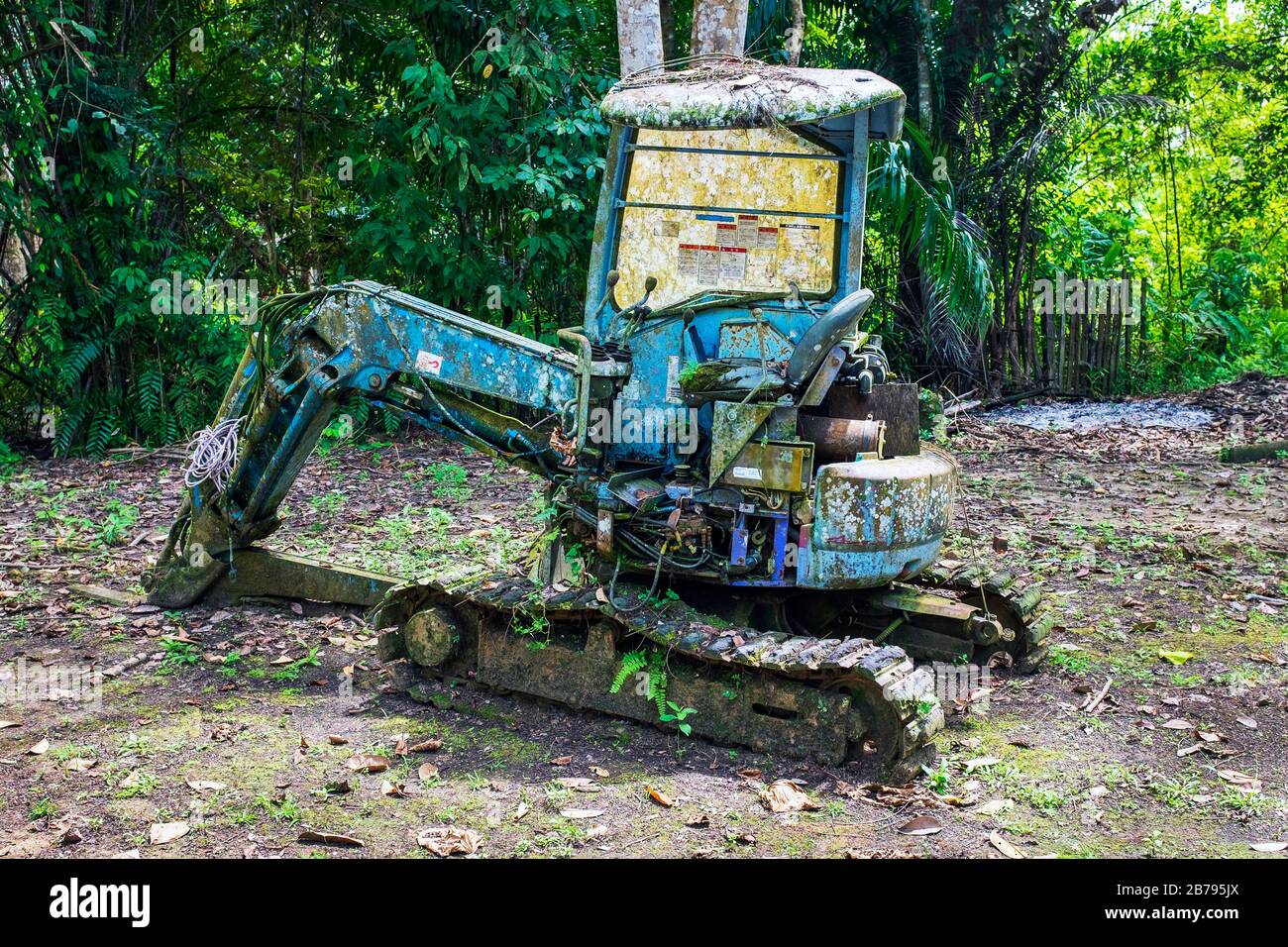 Miniexcavadora Komatsu abandonada, desaprovechada y corrosiva en la selva tropical de Borneo, Malasia Foto de stock