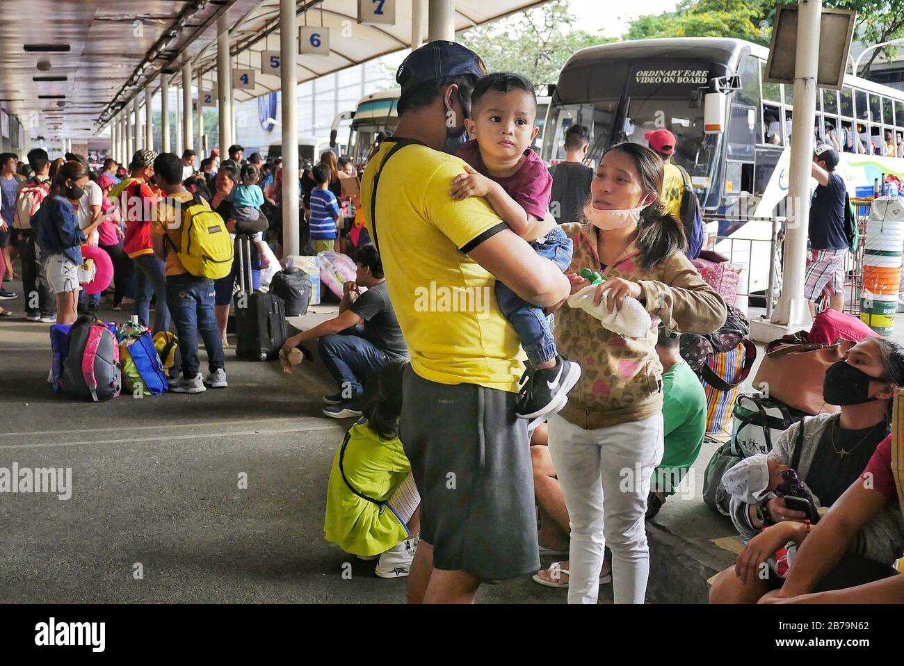 Ciudad De Quezon, Filipinas. 14 de marzo de 2020. Una madre aplicando alcohol de frotamiento sobre su hijo mientras esperan su viaje en autobús a casa mientras el país se prepara para una estricta cuarentena comunitaria contra el coronavirus. Crédito: George Buid/Zuma Wire/Alamy Live News Foto de stock