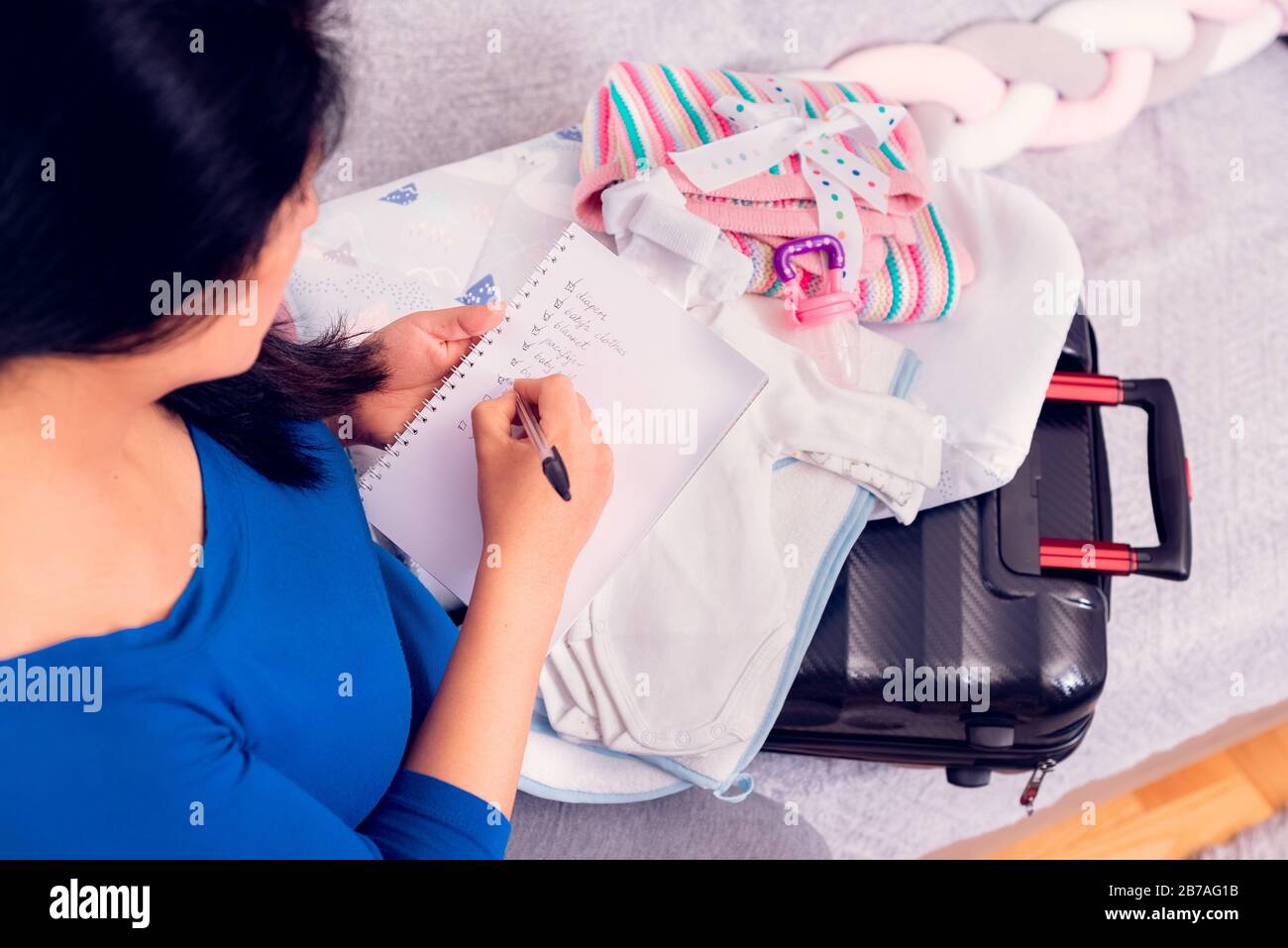 vanidad salto gráfico Mujer embarazada que hace la lista de verificación mientras que el embalaje  de la maleta con ropa de bebé recién nacido para el hospital Fotografía de  stock - Alamy