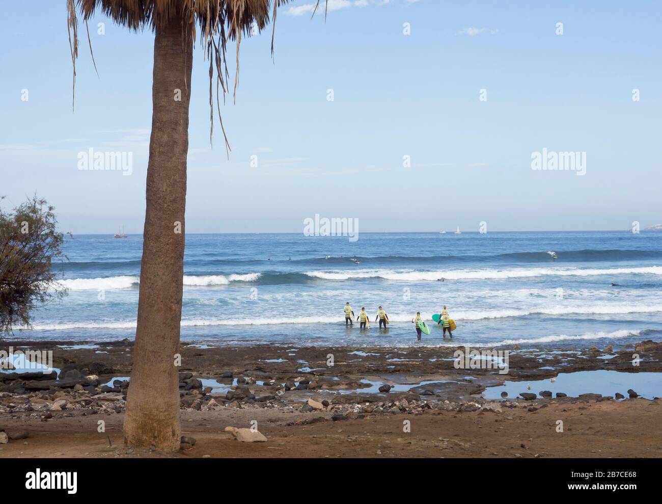 Un grupo de turistas que vadean hacia el océano Atlántico para aprender a surfear las olas, Playa de las américas, Tenerife Islas Canarias España Foto de stock