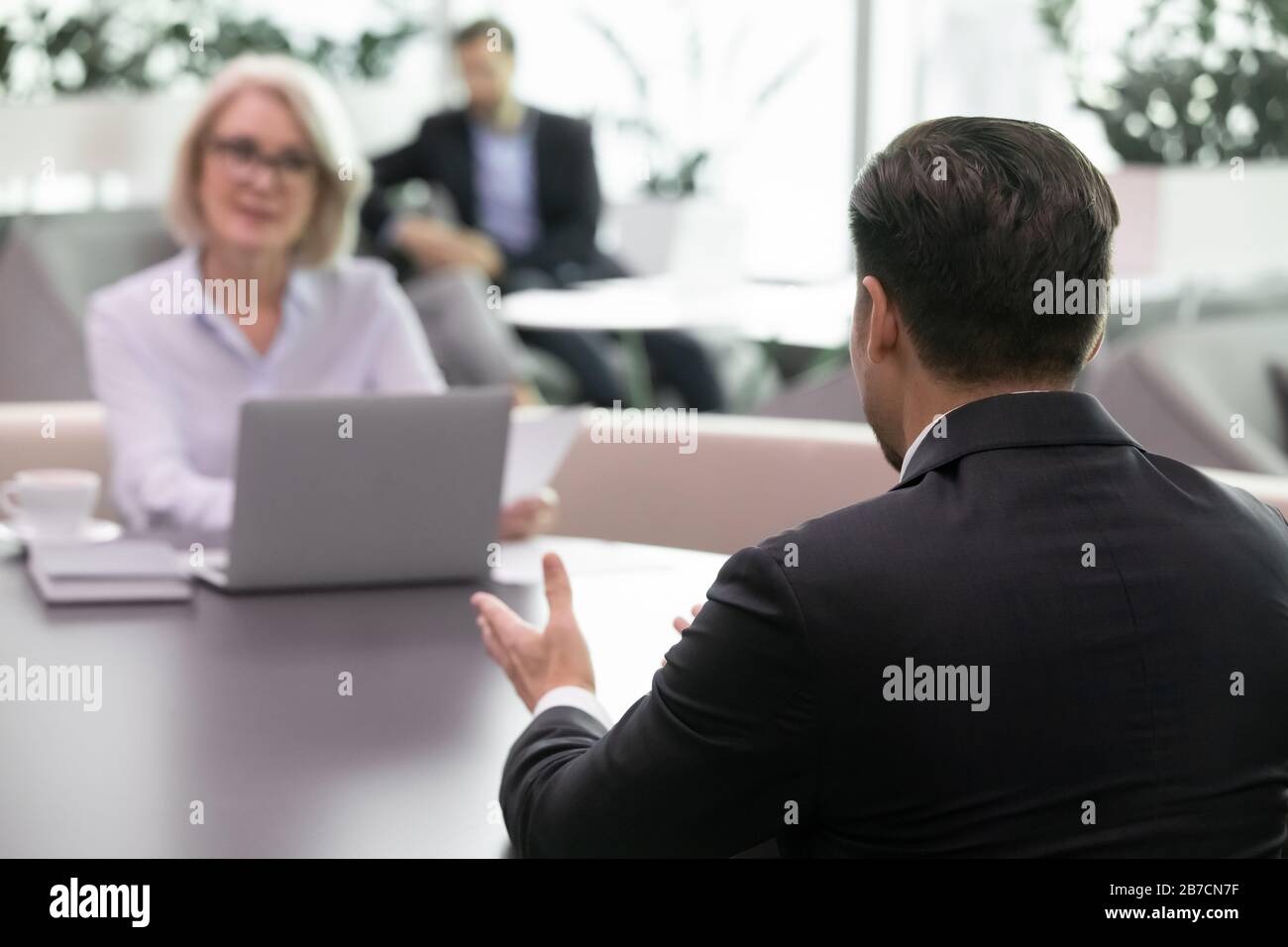 Vista posterior del candidato masculino hablar con el empleador en la entrevista Foto de stock