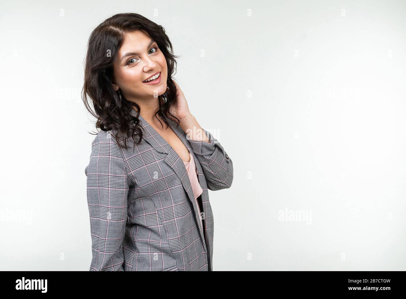 mujer bonita con pelo negro en una chaqueta gris a cuadros para la oficina  sobre un fondo blanco con espacio de copia Fotografía de stock - Alamy