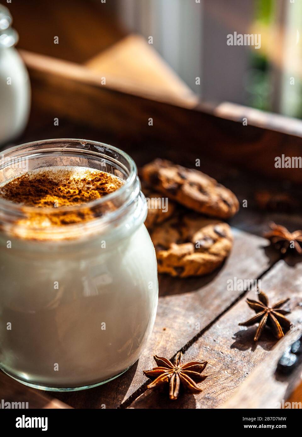 Primer plano de una taza de Sahlep turco caliente en una superficie rústica con bastones de canela y galletas Foto de stock