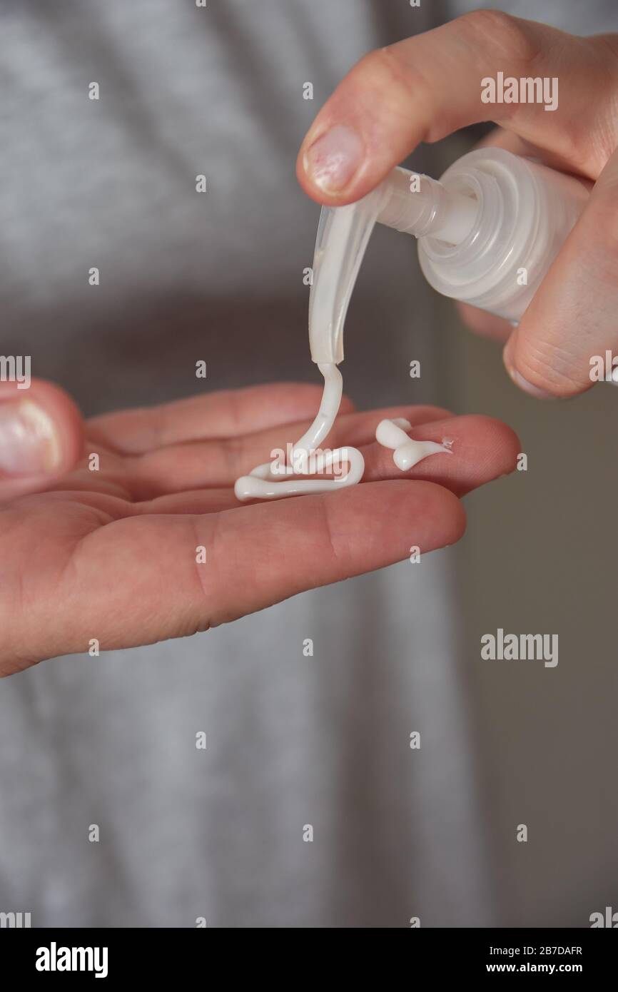 Mujer mano usando dispensador para aplicar crema sobre la piel con Psoriasis Foto de stock