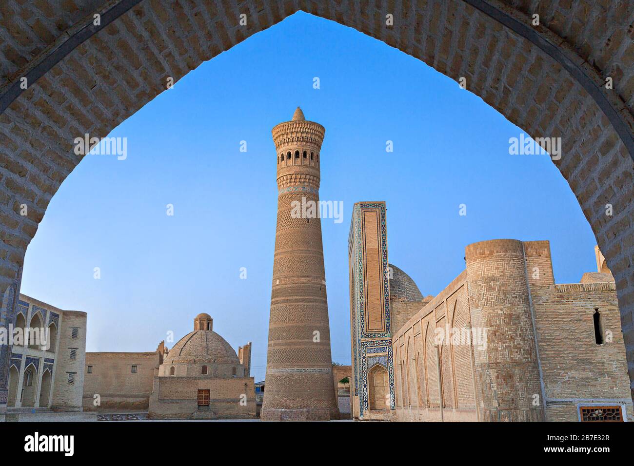 Mezquita y Minarete POI Kalon, al amanecer, a través de un arco, en Bujara, Uzbekistán Foto de stock