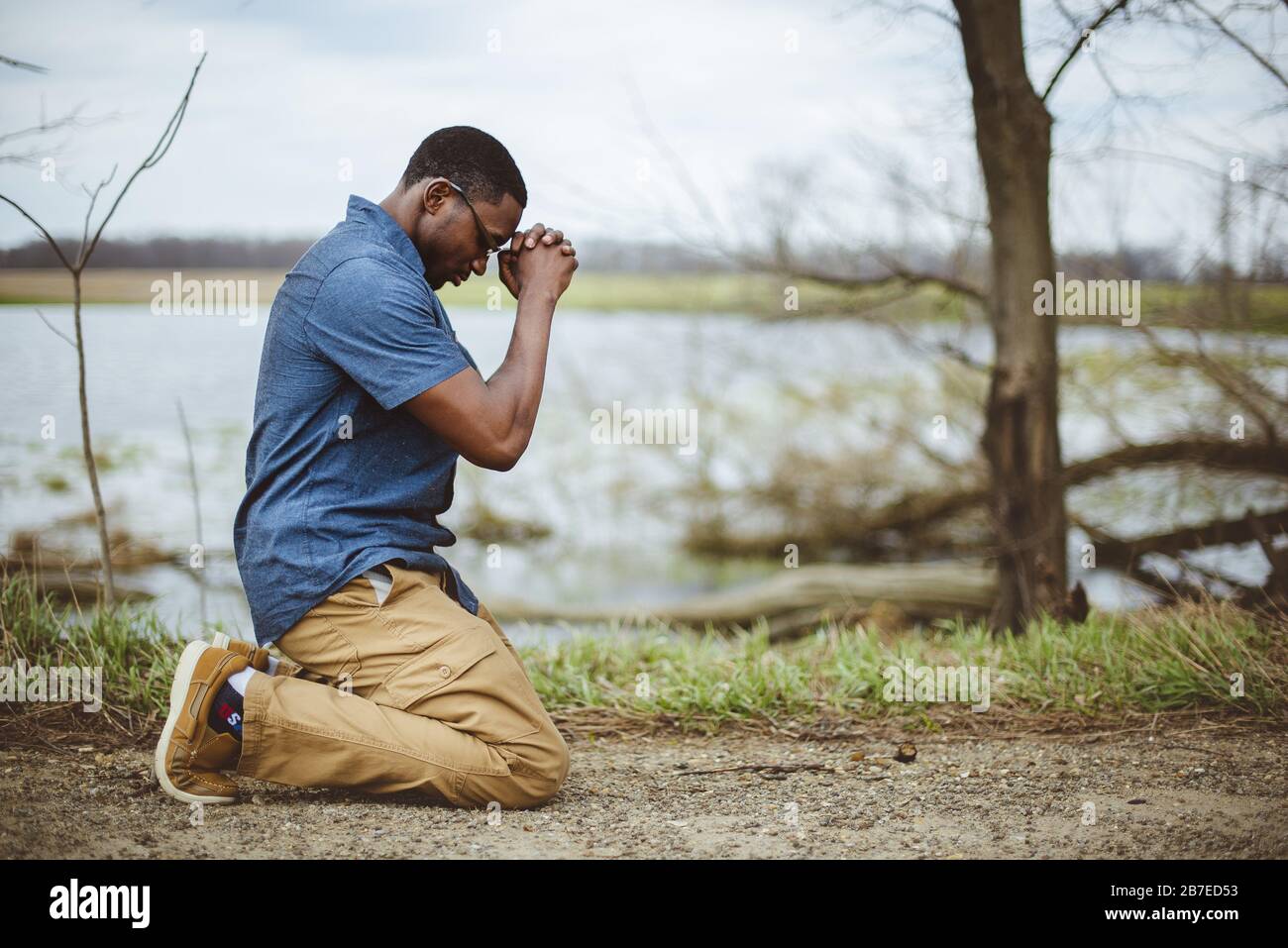 Un disparo vertical de un hombre afroamericano orando de rodillas  Fotografía de stock - Alamy