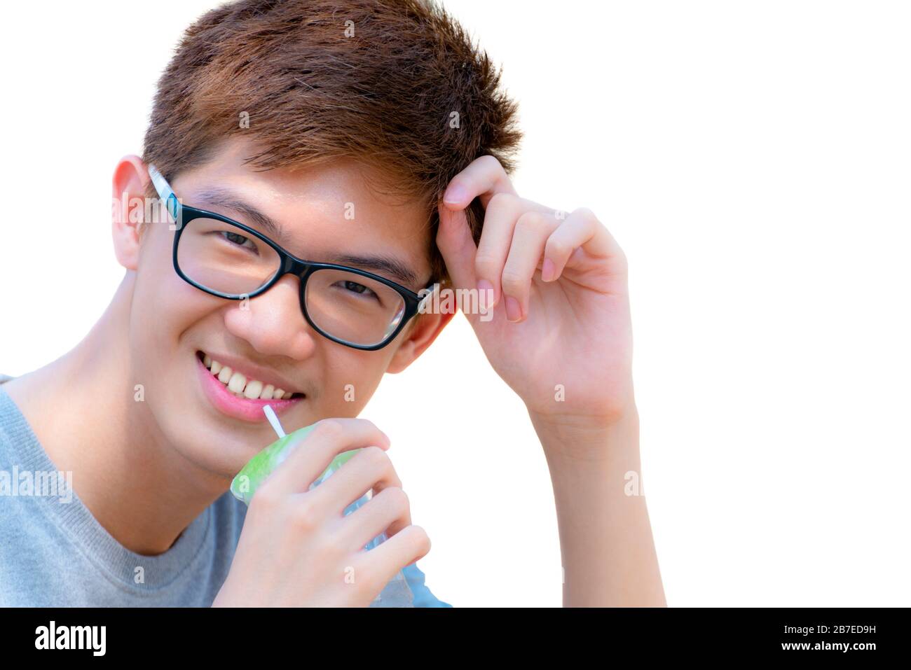Primer plano cara Asia hermoso adolescente niño con gafas de agua potable de la paja en la taza de plástico, retrato alegre hipster joven hombre están sonriendo con Foto de stock