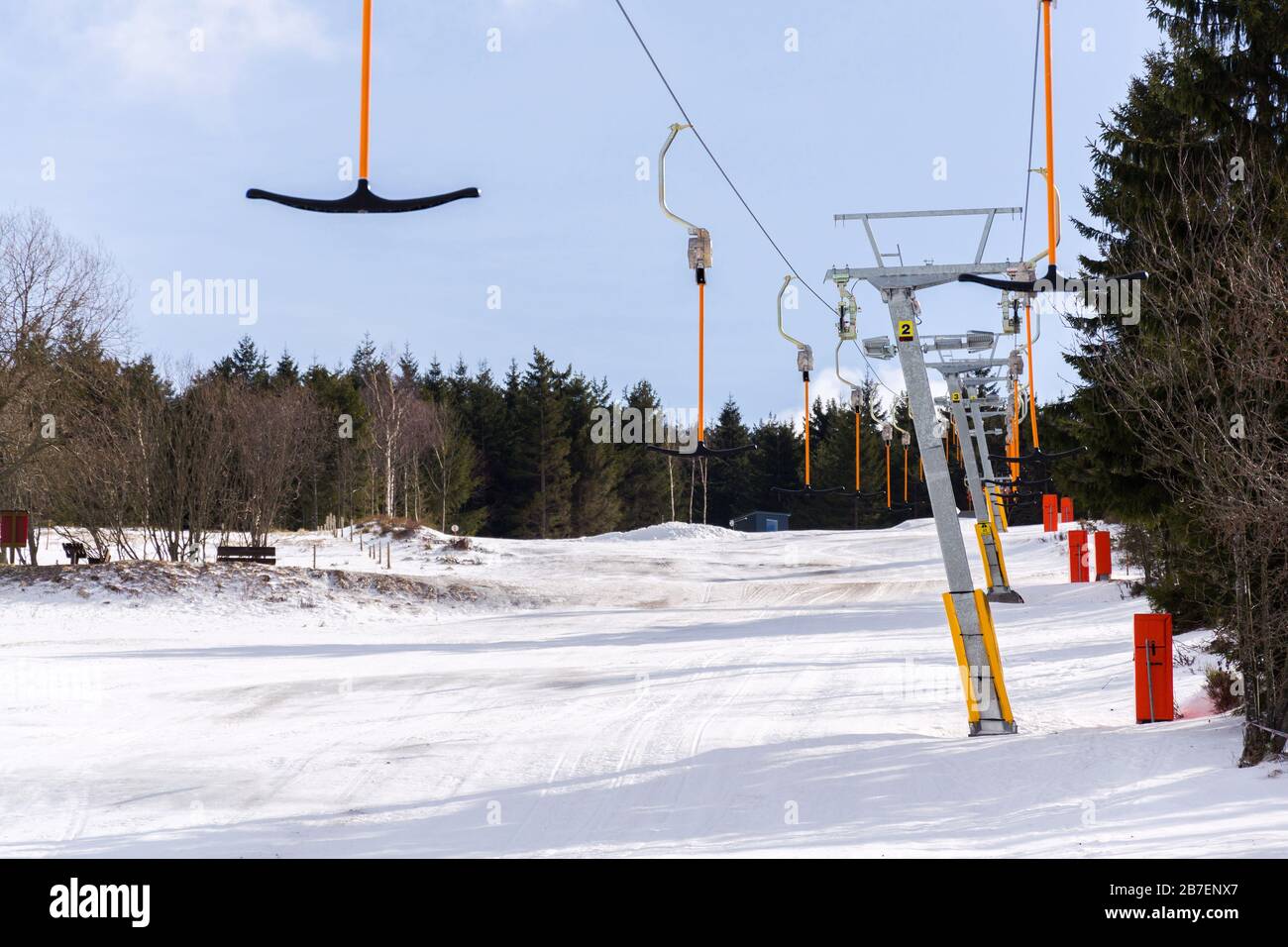 Elevador de superficie de barra en T detenido en pistas vacías, concepto de fin de temporada de esquí, pendiente con nieve desaparecida, invierno soleado o día de primavera Foto de stock