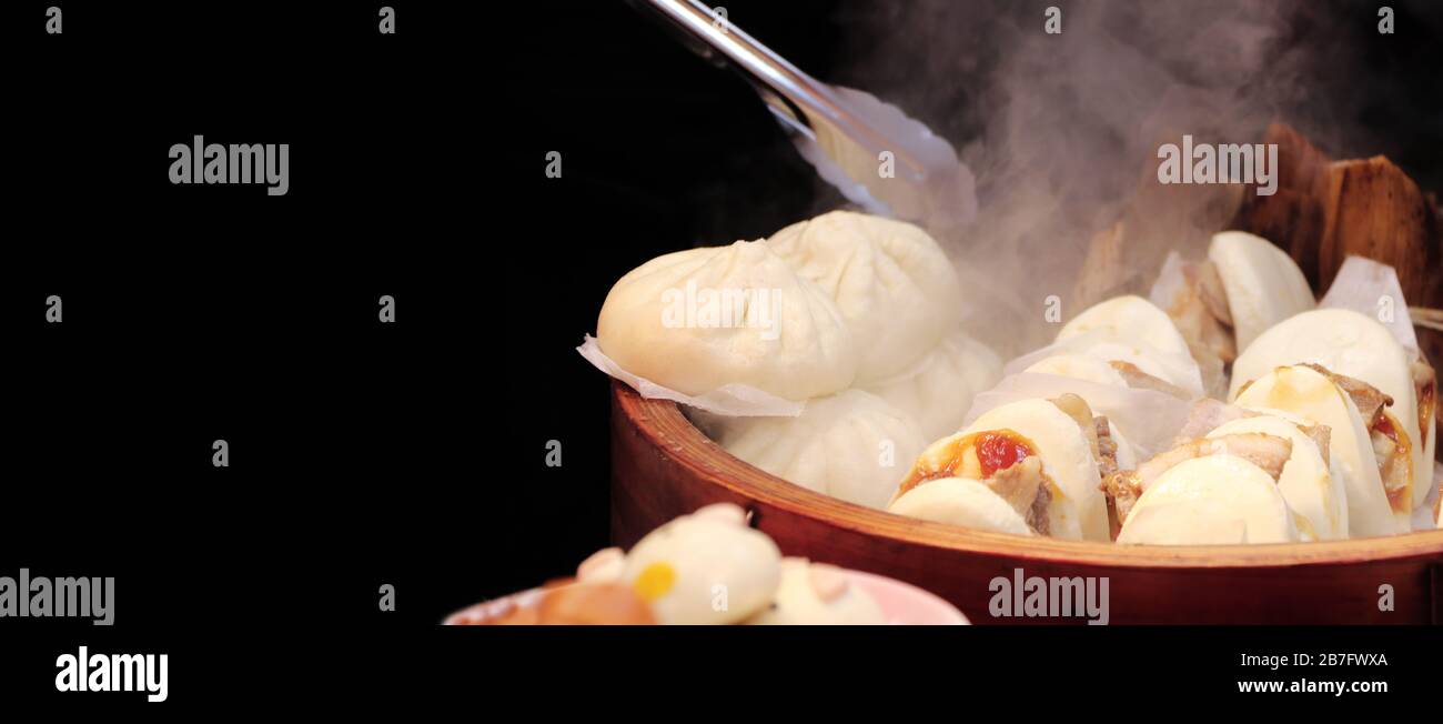 Cocina de bollos al vapor (mantou) de comida rápida tradicional china. Banner horizontal con comida asiática sobre fondo negro. Plantilla de simulación. Copiar espacio fo Foto de stock