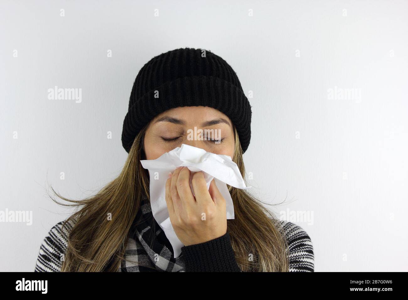 Mujer enferma usando un gorro y usando un pañuelo para estornudar y soplar  la nariz Fotografía de stock - Alamy