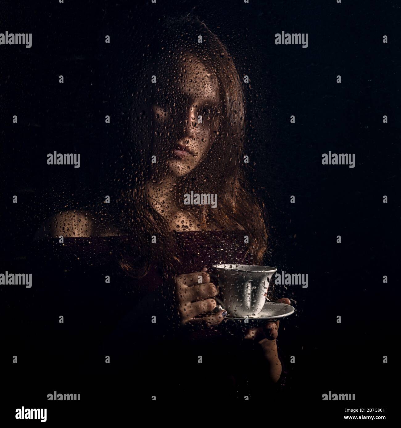 Duquesa Arcaico Coherente una chica joven y agradable bebe café detrás del vaso mojado, gotas de  lluvia en el vaso Fotografía de stock - Alamy