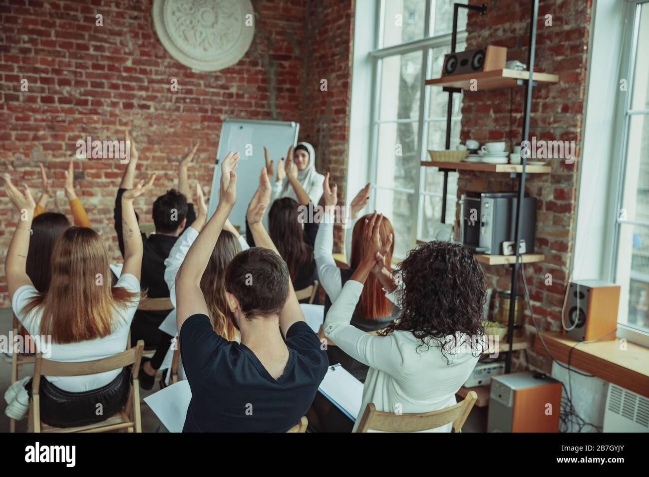 Una oradora musulmana que da una presentación en el salón del taller. Audiencia o sala de conferencias. Los participantes aplauden a la audiencia. Evento de conferencia, formación. Educación, diversidad, concepto inclusivo. Foto de stock