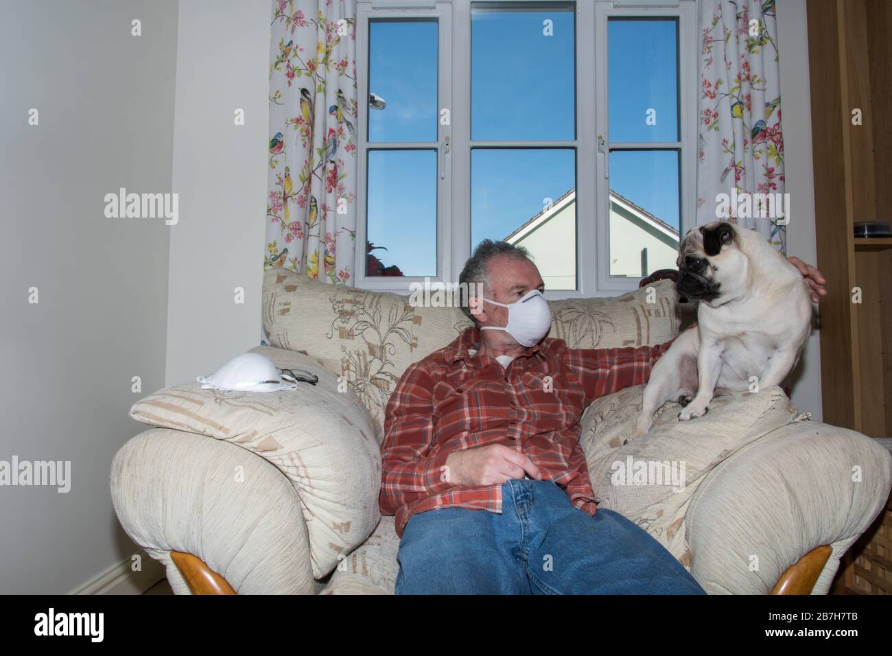Hombre en casa con mascarilla facial autoaislante Foto de stock